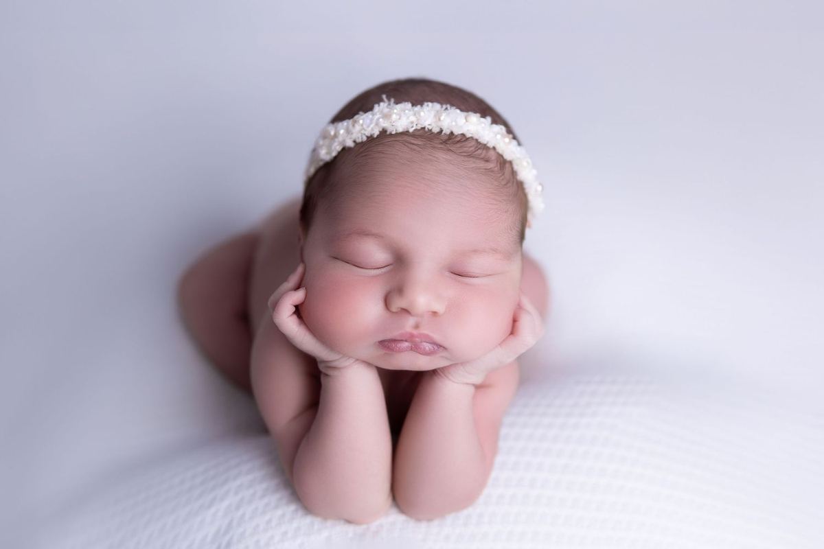 Sleeping newborn resting her head on her hands, photographed by Juliana