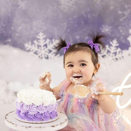 Baby girl smashing a purple first birthday cake