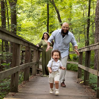 Family running on a wooden bridge in the woods