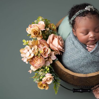Newborn in a wooden bowl with peach roses